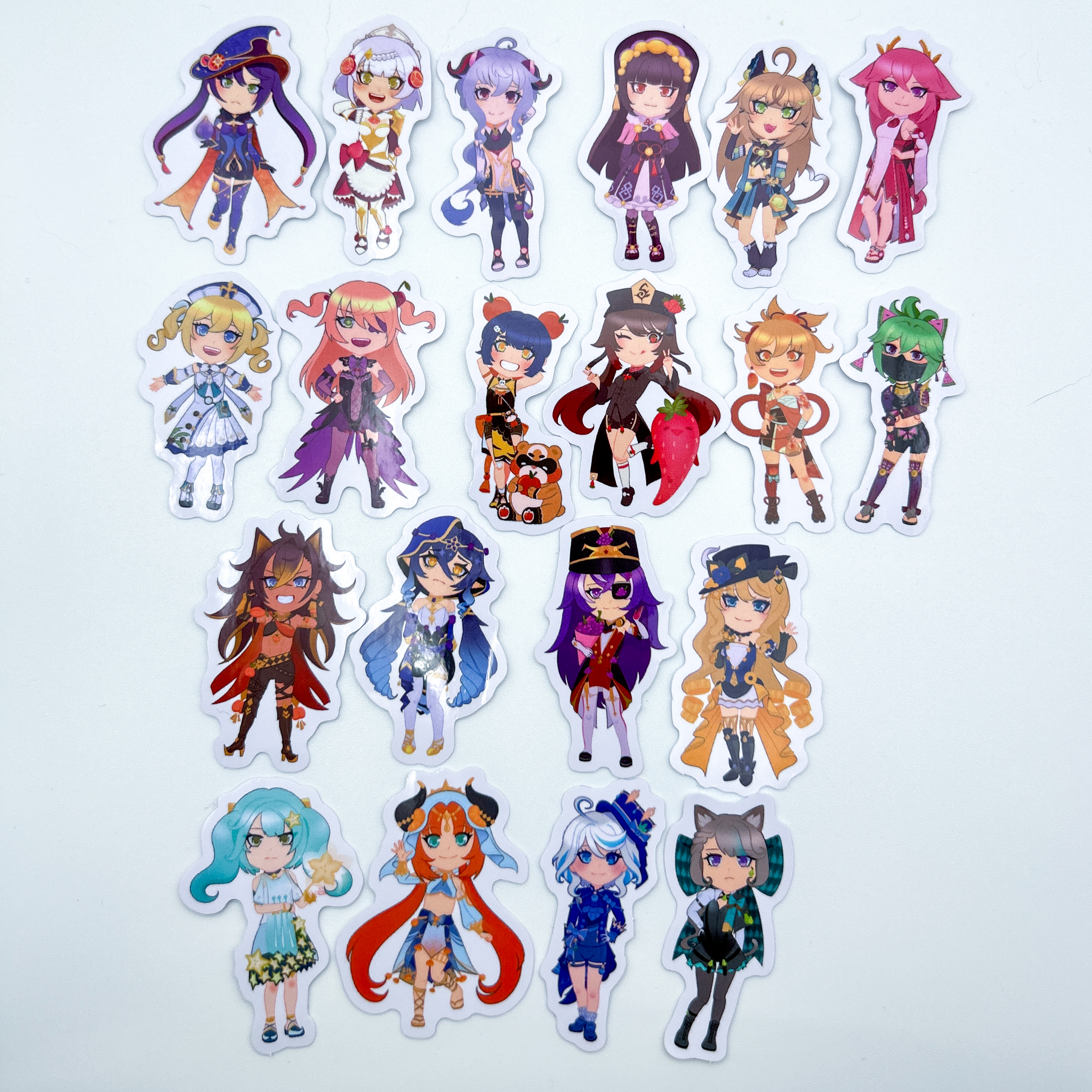 Genshin Fruit-Themed Mini Stickers - 20 miniature die-cut vinyl stickers, each depicting a different female character from Genshin Impact. Each character has a different fruit integrated into their design. The characters are as follows: Mona (fig), Noelle (pomegranate), Ganyu (mangosteen), YunJin (lemon), Kirara (honeydew), Yae Miko (dragonfruit), Barbara (coconut), Fischl (cherry), Xiangling (apple), Hu Tao (strawberry), Yoimiya (mango), Kuki Shinobu (watermelon), Dehya (peach), Layla (blackberry), Chevreuse (grape), Navia (pineapple), Faruzan (starfruit), Nilou (orange), Furina (blueberry), and Lynette (pear).